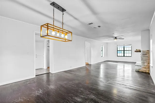 an empty room with wooden floor cabinet and windows