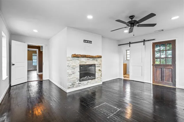 an empty room with wooden floor a ceiling fan a fireplace and windows