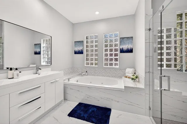 a spacious bathroom with a tub sink and mirror