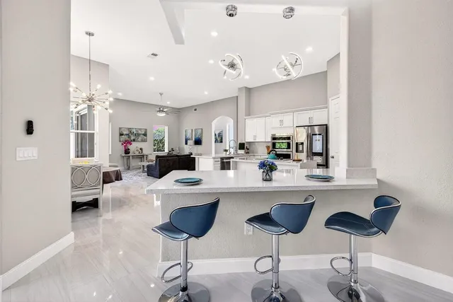 a kitchen with stainless steel appliances a dining table chairs sink and cabinets