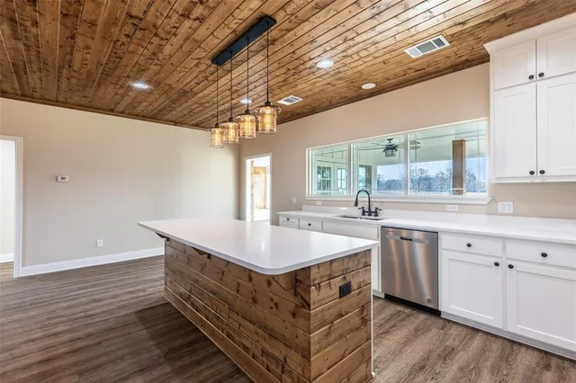 a kitchen with kitchen island granite countertop a sink and a white wooden cabinets