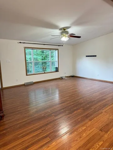 an empty room with wooden floor chandelier fan and windows