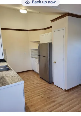 a kitchen with a refrigerator and a wooden floor