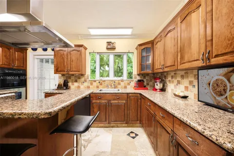 a kitchen with granite countertop a sink a counter space appliances and cabinets