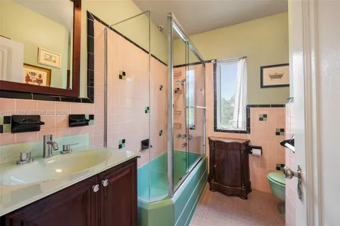 a bathroom with a granite countertop sink a mirror a bathtub and shower