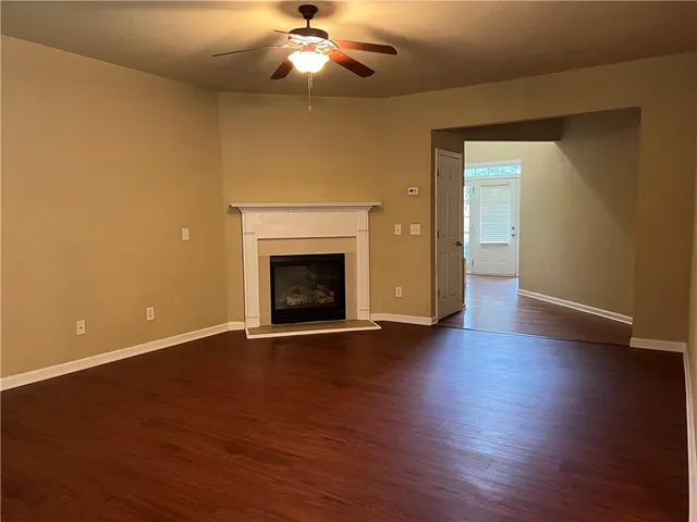 an empty room with wooden floor a ceiling fan and a fireplace