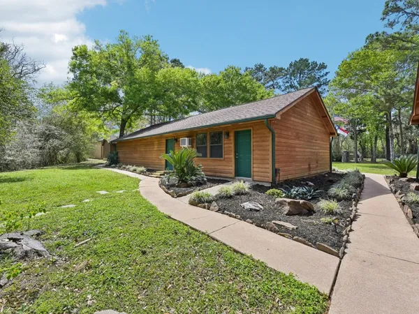 a backyard of a house with plants and large tree