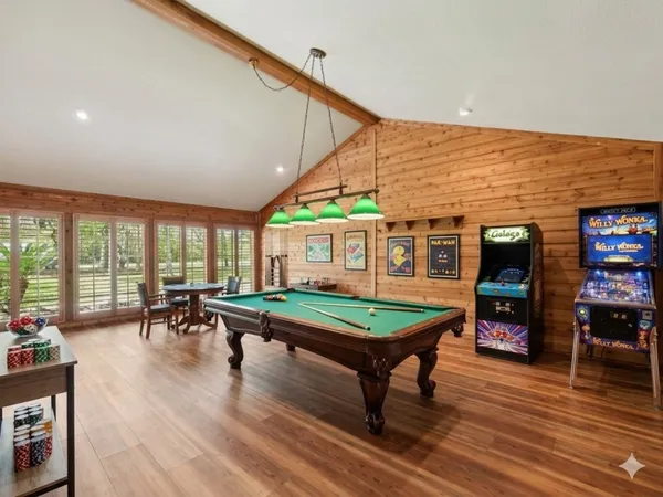a living room with furniture pool table wooden floor and a large window