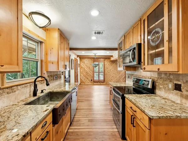 a kitchen with stainless steel appliances granite countertop a sink a stove top oven a counter space and cabinets