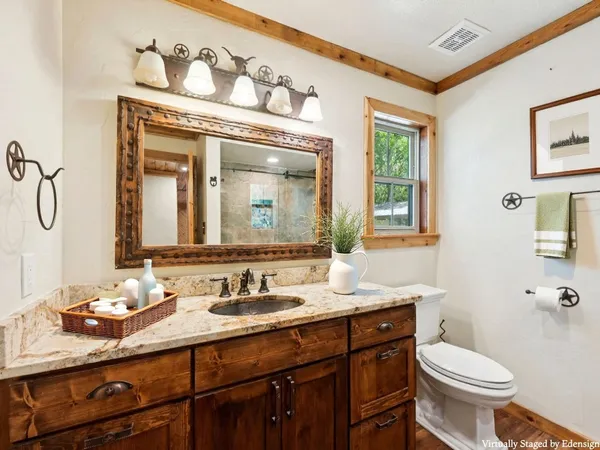 a bathroom with a granite countertop toilet sink and mirror