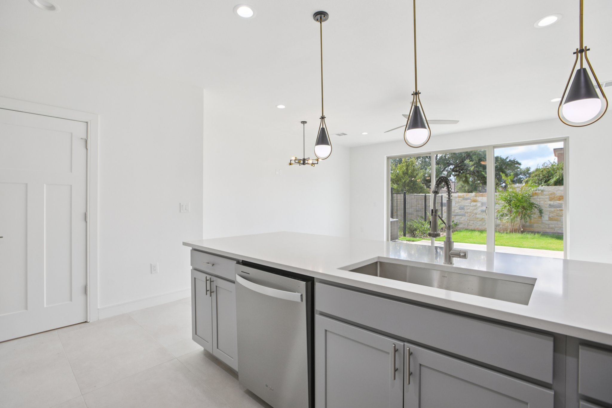 202 Tesla Circle Austin, TX 78681 - Photo 13 of 35 Kitchen with stainless steel dishwasher, gray cabinetry, pendant lighting, and light stone countertops