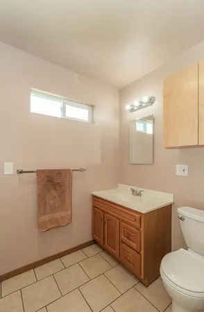 a bathroom with a toilet a sink a mirror and a window