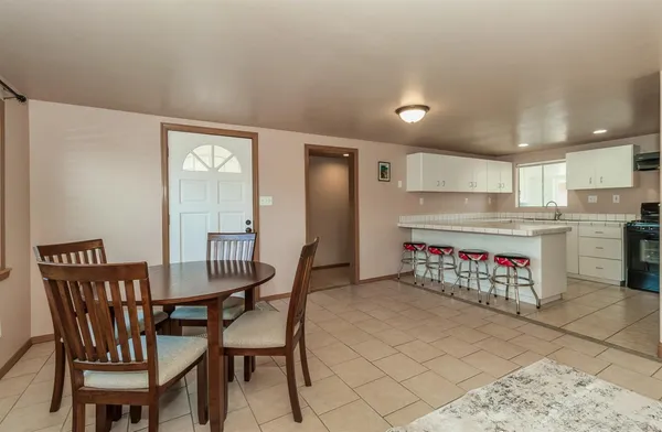 a kitchen with stainless steel appliances kitchen island granite countertop a refrigerator a stove a dining table and chairs