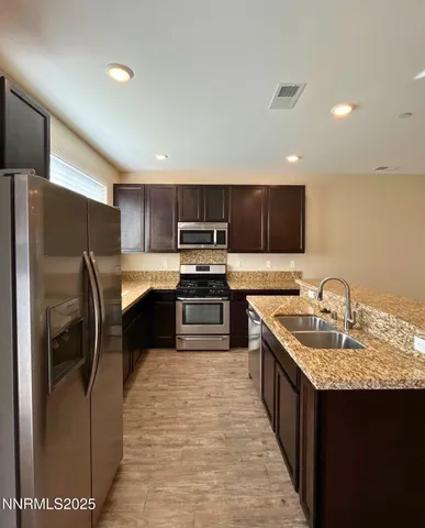 a kitchen with stainless steel appliances granite countertop a refrigerator a stove a sink a microwave and a refrigerator