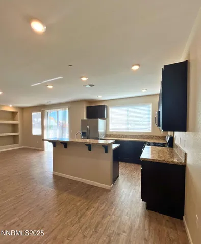 a large living room with stainless steel appliances kitchen island granite countertop a large window