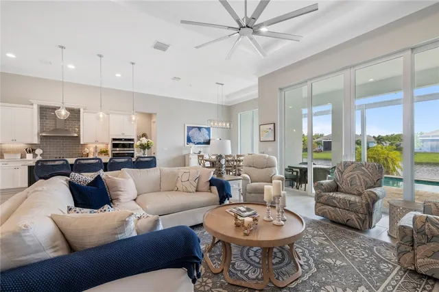 a living room with furniture a rug potted plant and a large window