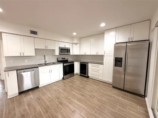 a kitchen with granite countertop white cabinets and stainless steel appliances