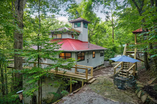 a backyard of a house with table and chairs under an umbrella