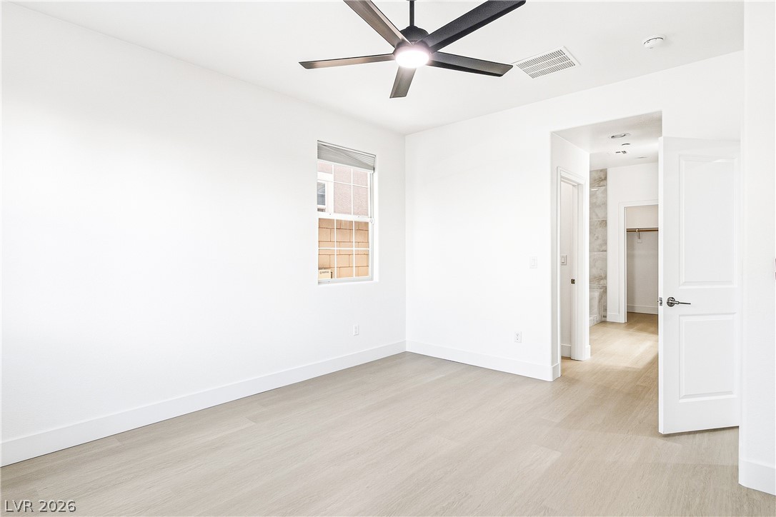 2182 Trivero Street Henderson, NV 89044 - Photo 19 of 50 Smooth wood-style flooring and tall ceilings anchor this pristine, minimalist bedroom space.