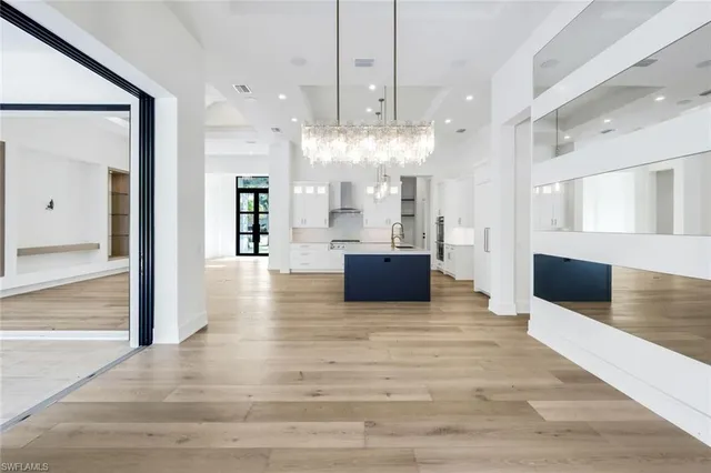 a large white kitchen with a large island oven a sink and a large window