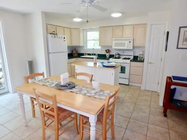 a kitchen with stainless steel appliances granite countertop a dining table chairs and refrigerator