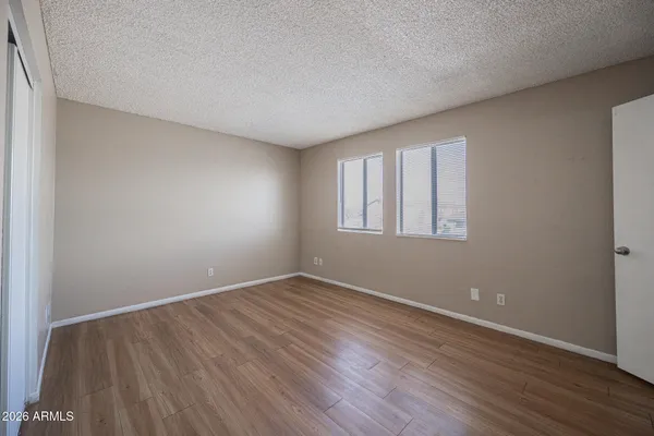 an empty room with wooden floor and windows