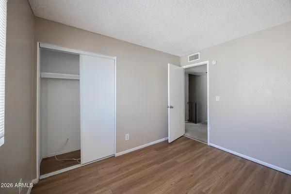 a view of an empty room with wooden floor and closet