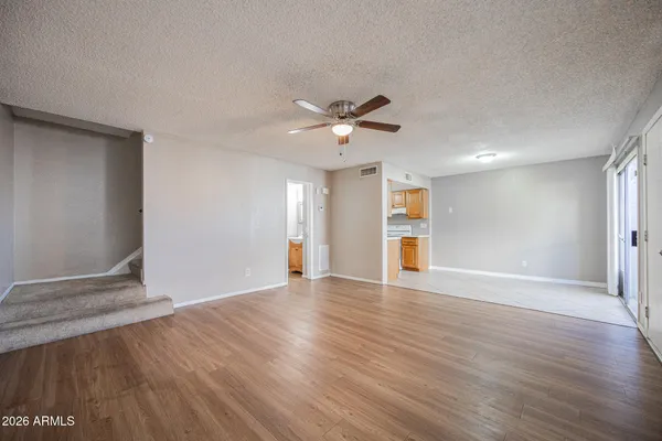 a view of an empty room with wooden floor and a ceiling fan