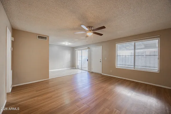 a view of an empty room with a window and wooden floor