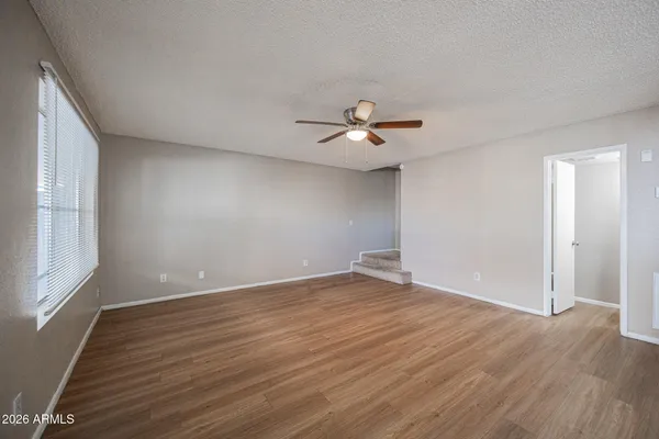 a view of an empty room with a window and wooden floor