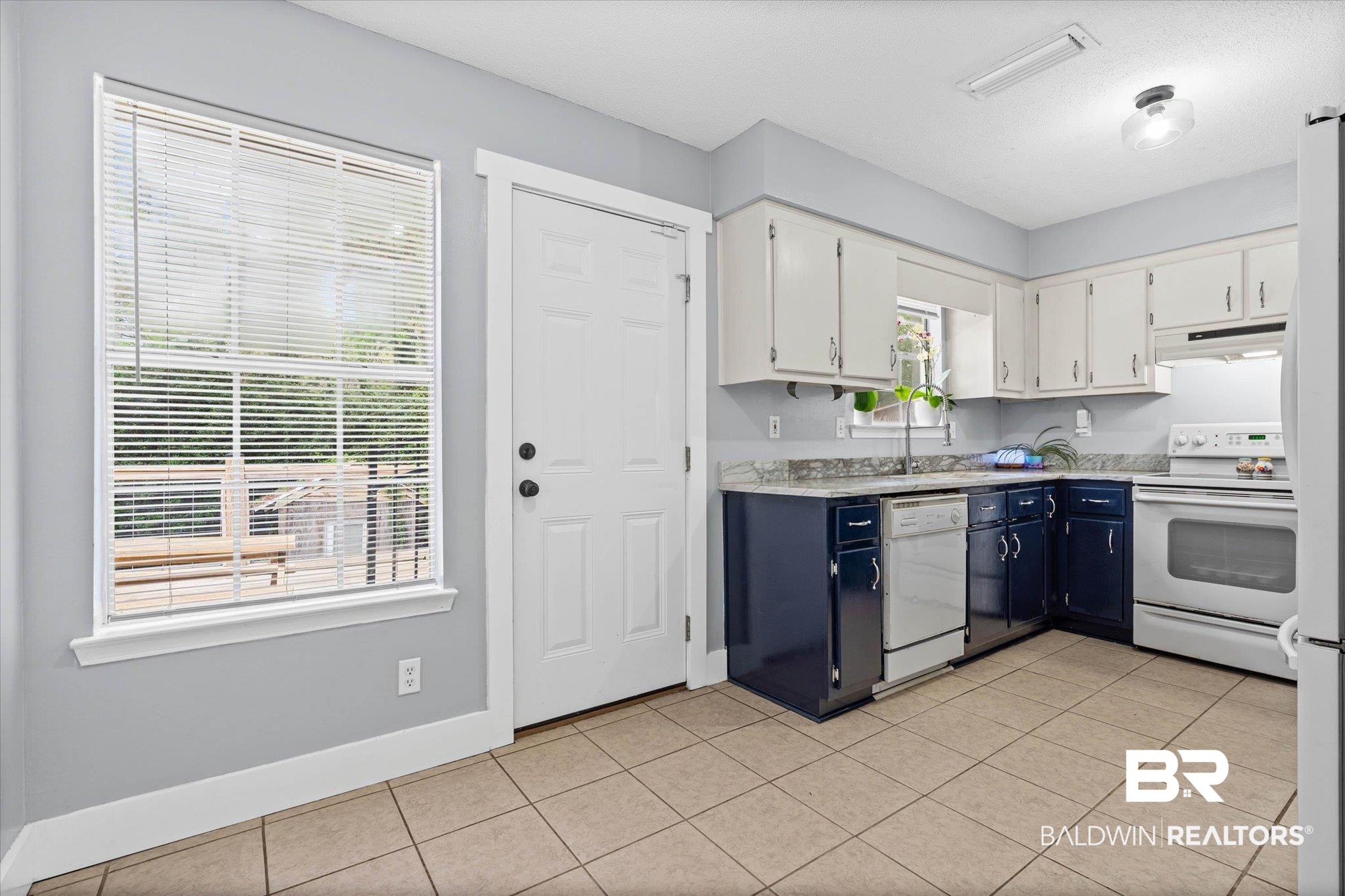 1849 Ranch House Drive Semmes, AL 36575 - Photo 7 of 23 Kitchen featuring two tone color scheme, light countertops, light tile patterned floors, and white appliances