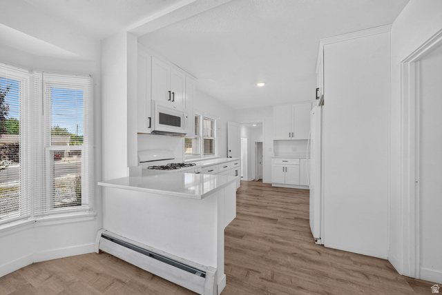 220 East Greenwood Avenue Midvale, UT 84047 - Photo 7 of 46 Bright kitchen featuring white cabinetry, light-toned wood-finish flooring, and white countertops
