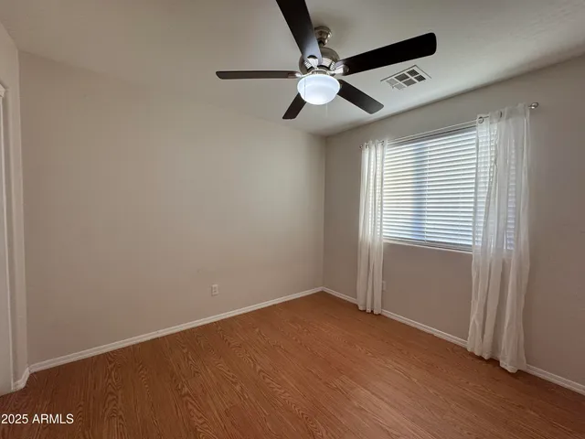 an empty room with wooden floor fan and windows