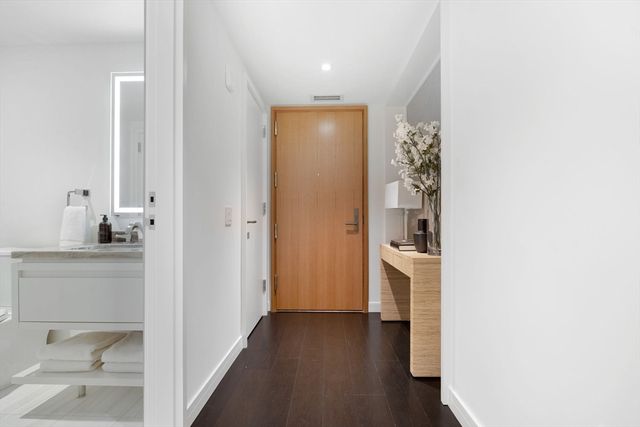 a view of a hallway with wooden floor and a bathroom