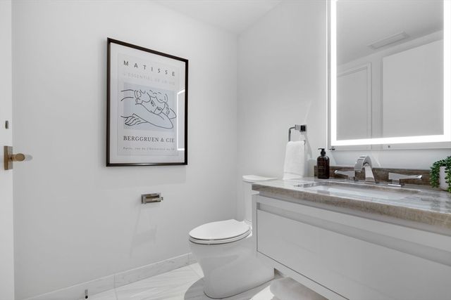 a bathroom with a granite countertop toilet sink and mirror