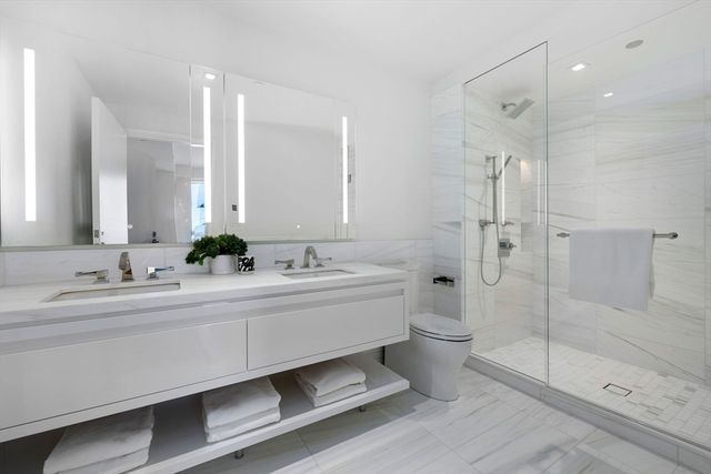 a bathroom with a double vanity sink toilet and shower