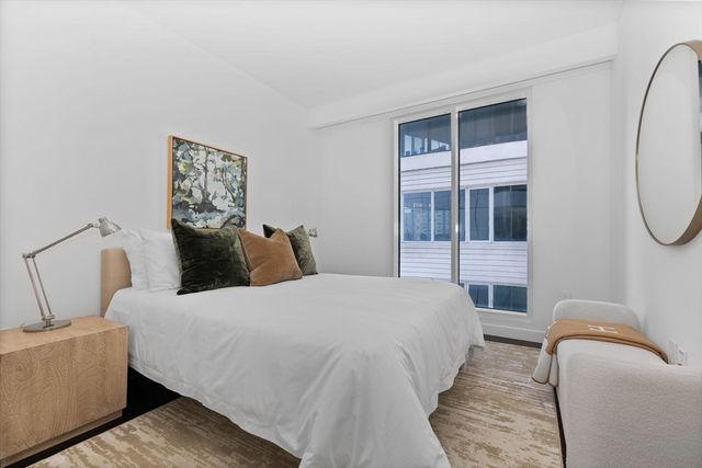 a bedroom with a bed a mirror and a window