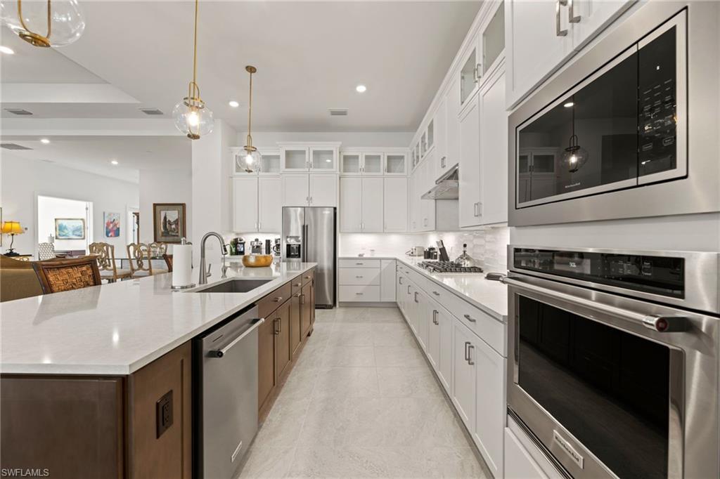 16140 Verilyn Circle Naples, FL 34110 - Photo 10 of 44 a large white kitchen with stainless steel appliances kitchen island granite countertop a large stove a sink dishwasher and white cabinets with wooden floor