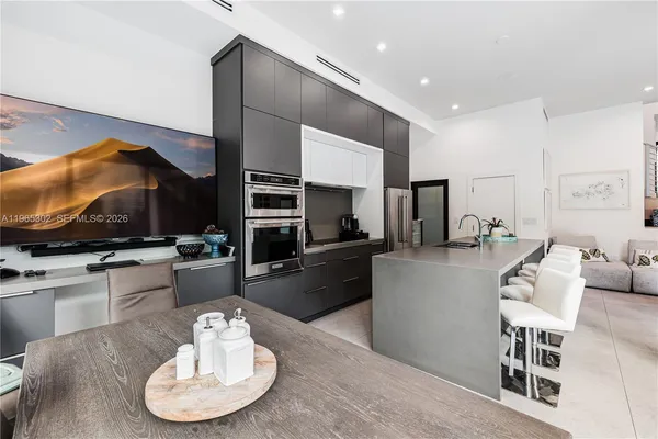 a kitchen with stainless steel appliances kitchen island granite countertop a sink a stove a dining table and chairs