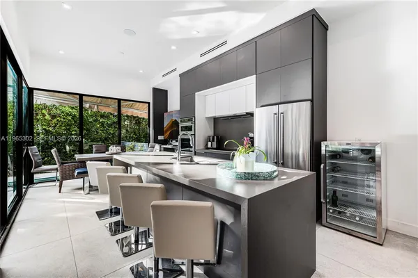 a room with stainless steel appliances kitchen island granite countertop a table chairs and a view of living room