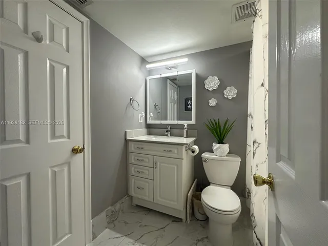 a bathroom with a granite countertop toilet a sink and a mirror