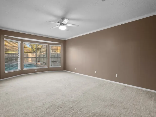 a view of an empty room with a chandelier fan and a window