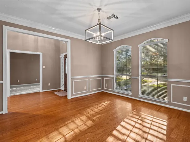 a view of a livingroom with wooden floor a ceiling fan and windows