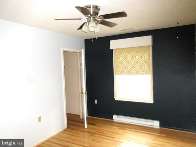 a view of an empty room with window and a ceiling fan
