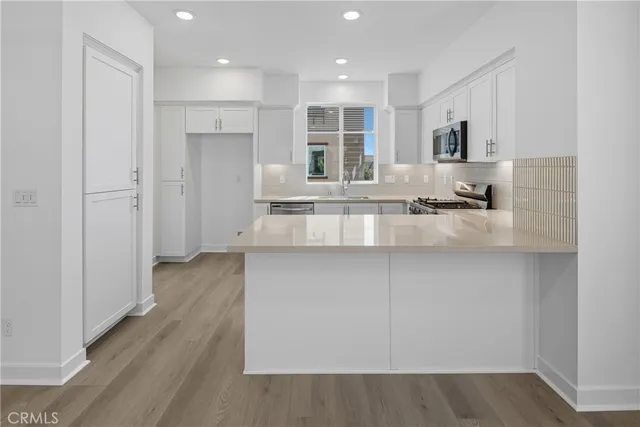 a large white kitchen with kitchen island a sink stainless steel appliances and cabinets