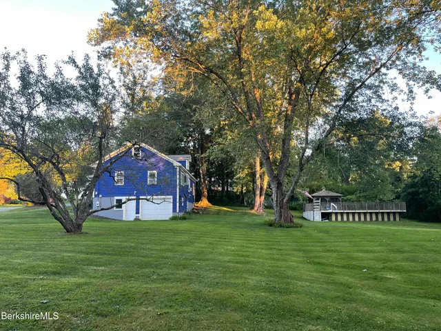 a view of a big house with a big yard and large trees