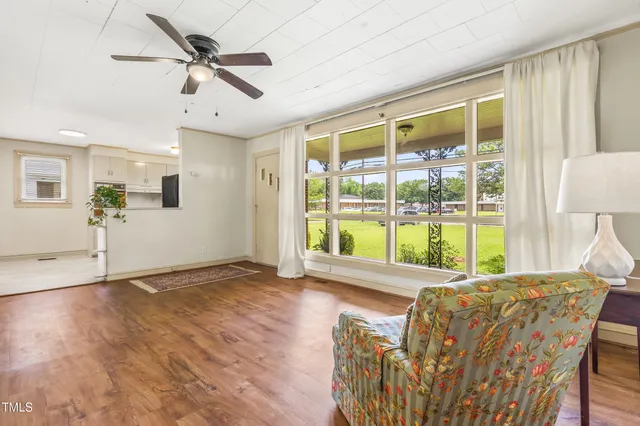 a view of an empty room with wooden floor and a window