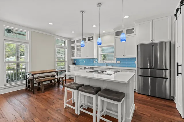 a kitchen with kitchen island a stove a refrigerator a dining table and chairs with wooden floor