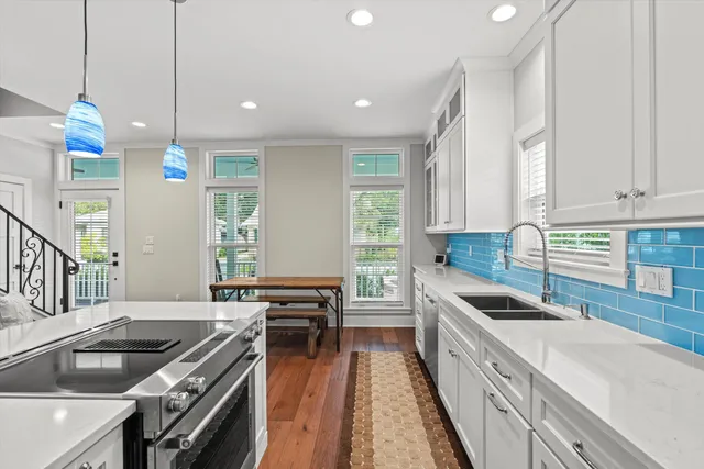 a kitchen with stove a sink dishwasher and a refrigerator with wooden floor