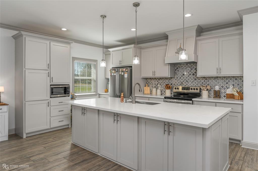 396 Collinswood Road Stonewall, LA 71078 - Photo 16 of 32 a kitchen with stainless steel appliances granite countertop a sink a stove a refrigerator and white cabinets with wooden floor